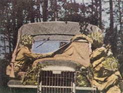 [FIGURE 20. Blankets, shelter halves, or pieces of dark-colored burlap or osnaburg are expedients for covering the reflecting surface of a windshield quickly. Foliage may be used to cover headlights.]