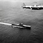 A Douglas SBD-3 Dauntless flies over the USS Enterprise (CV-6) and USS Saratoga (CV-3) near Guadalcanal in December 1942.